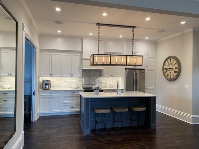 Kitchen — navy island, herringbone backsplash and linear pendant