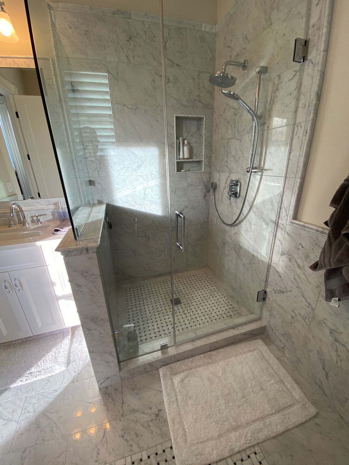Carrara marble bath renovation with frameless glass shower